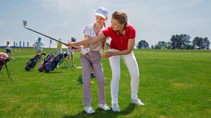 A golf instructor helping her client with her swing