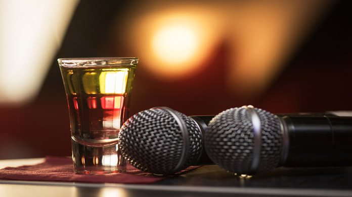 two microphones and a shot glass of liquor on a bar counter