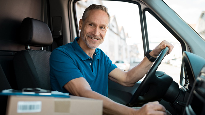 Man sitting behind the wheel of a delivery truck.