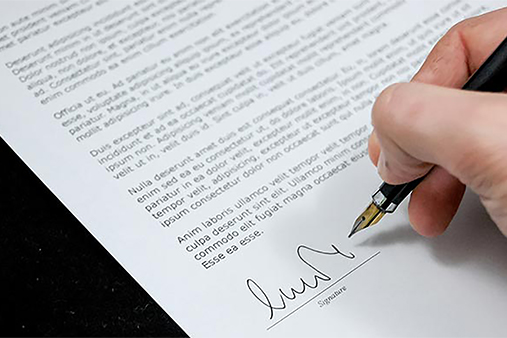 A closeup of a hand signing a document