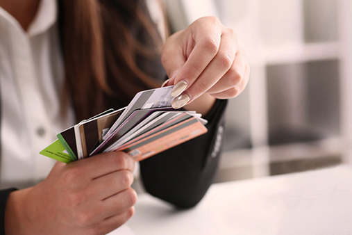 A person looking at a handful of credit cards