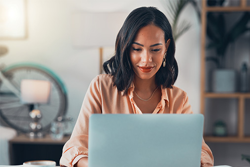 Woman smiling and looking at a computer with the 7 benefits of getting an EIN.