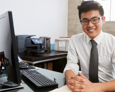 A smiling man sits at a computer including learns regarding corporate veils