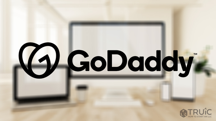 GoDaddy logo with computers in the background